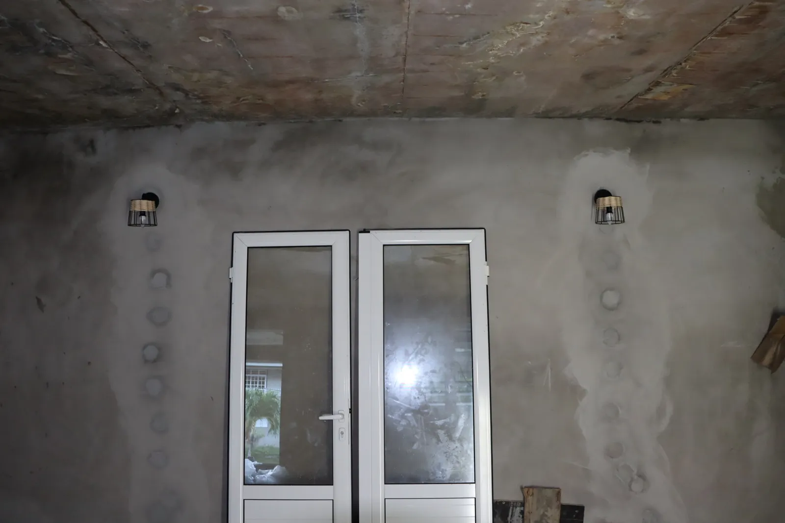 Boîtiers et gaines encastrés autour d'une baie vitrée avant enduit