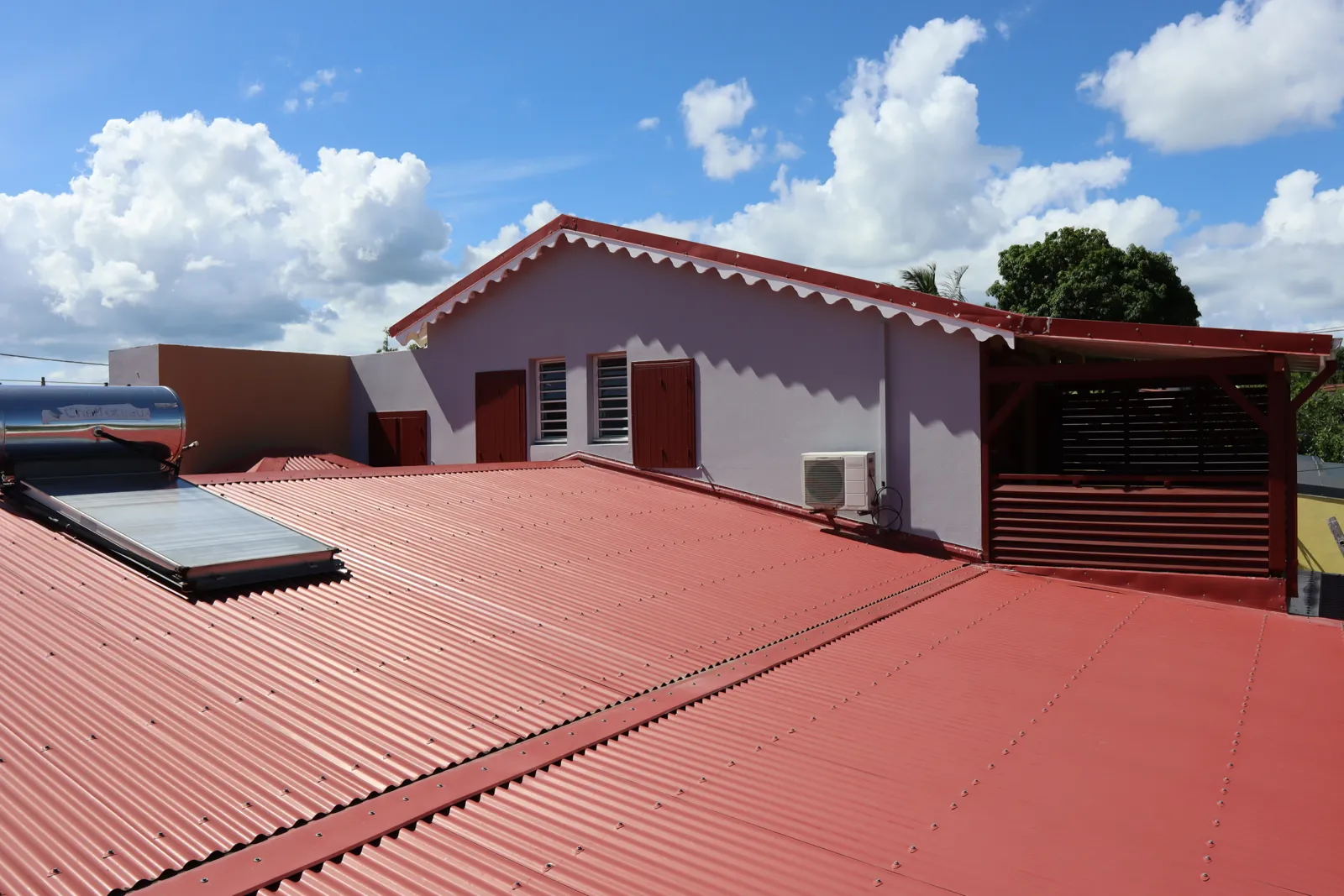 Toiture en tôle rouge et façade rénovée d'une maison créole