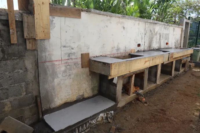 Coffrages bois et dalle béton coulée contre un mur maçonné