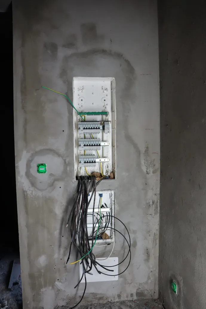 Tableau électrique encastré et arrivées de gaines dans un mur brut