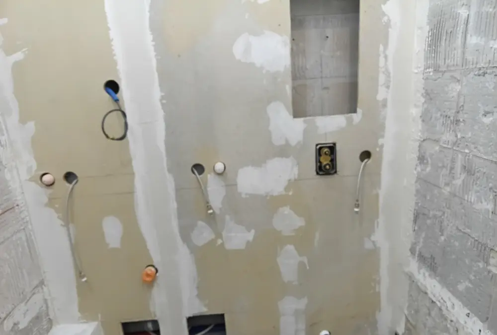 Parois en plaques de fibrociment avec attentes de plomberie dans une salle de bain en rénovation en Guadeloupe